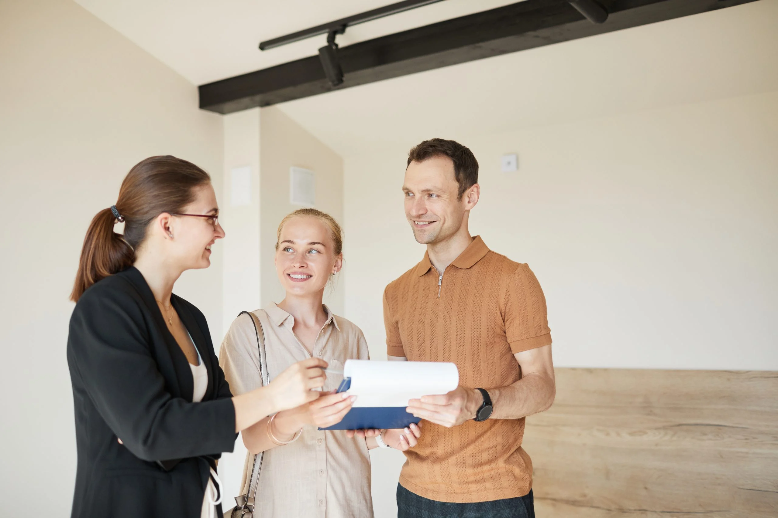 Waist up portrait happy couple signing contract with real estate agent apartment tour new house copy space